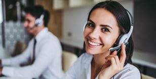 Uśmiechnięta kobieta rozmawia przez telefon na call center